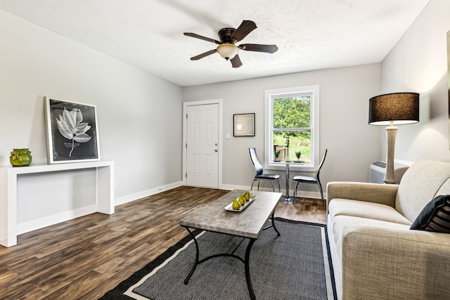 living room featuring ceiling fan, a textured ceiling, and dark hardwood / wood-style flooring