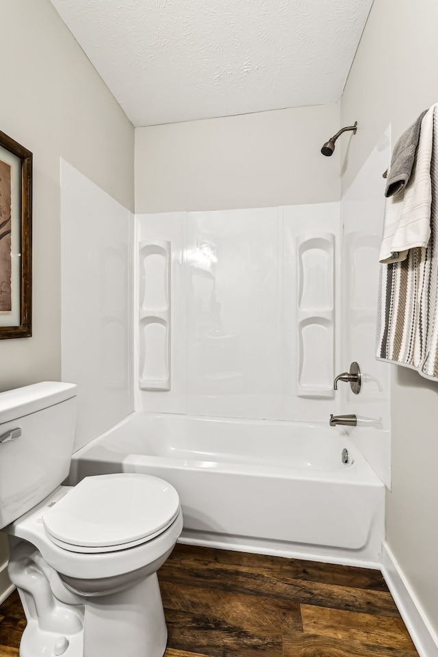 bathroom featuring shower / washtub combination, hardwood / wood-style floors, and toilet