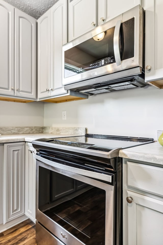 kitchen featuring stainless steel appliances, hardwood / wood-style floors, and white cabinetry