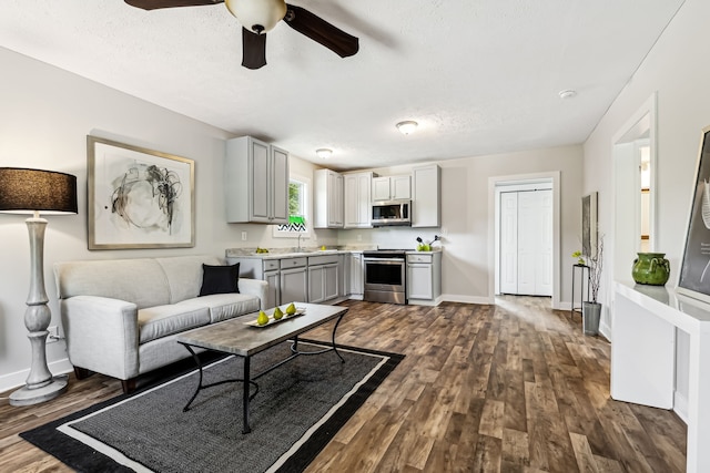 living room featuring a textured ceiling, ceiling fan, sink, and dark hardwood / wood-style flooring