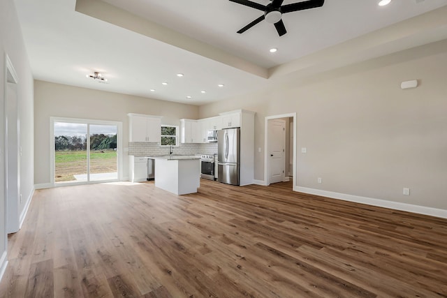 unfurnished living room featuring hardwood / wood-style flooring, ceiling fan, and sink