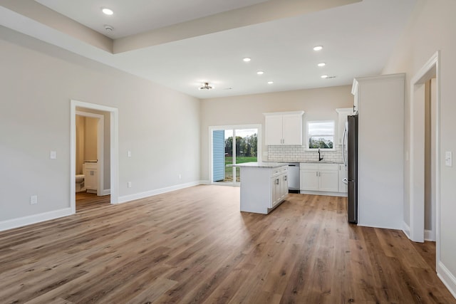 kitchen with stainless steel appliances, sink, light hardwood / wood-style flooring, a center island, and white cabinets