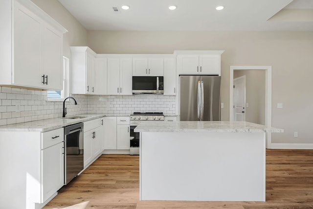 kitchen with white cabinets, appliances with stainless steel finishes, sink, and a kitchen island