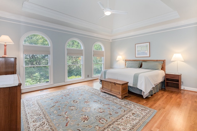 bedroom featuring ceiling fan, ornamental molding, a raised ceiling, and light hardwood / wood-style floors