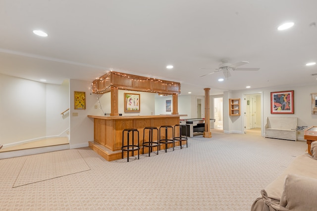 interior space with kitchen peninsula, a breakfast bar area, ceiling fan, and light colored carpet