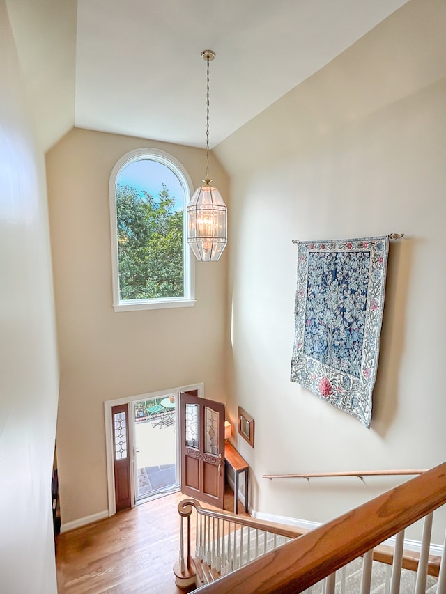 staircase with hardwood / wood-style flooring, vaulted ceiling, and a healthy amount of sunlight