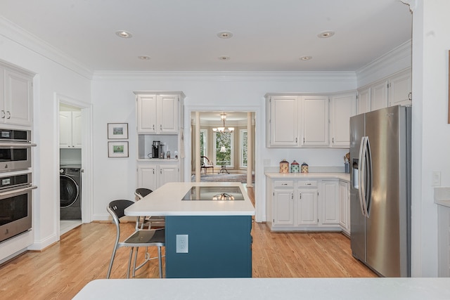 kitchen with a kitchen island with sink, white cabinetry, stainless steel appliances, washer / dryer, and light hardwood / wood-style floors