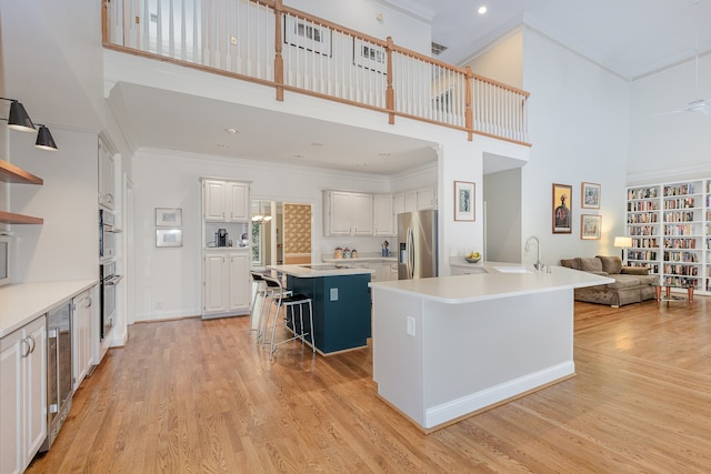 kitchen featuring white cabinetry, a breakfast bar, a kitchen island, stainless steel appliances, and a high ceiling