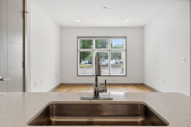 kitchen featuring light stone countertops, light wood-type flooring, and sink