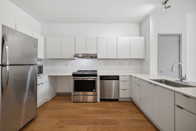 kitchen with light hardwood / wood-style floors, stainless steel appliances, sink, and white cabinets