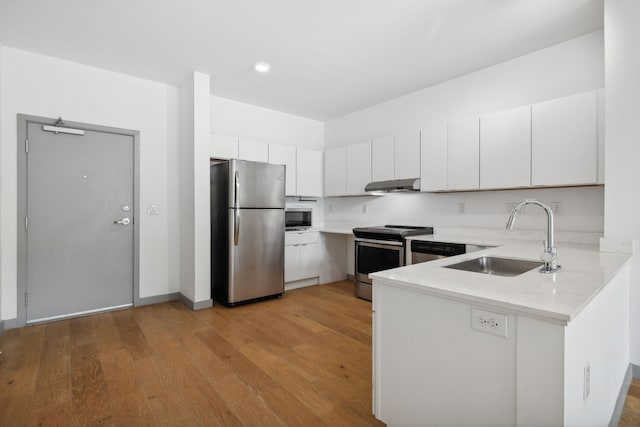 kitchen featuring white cabinets, light stone countertops, stainless steel appliances, light hardwood / wood-style flooring, and sink