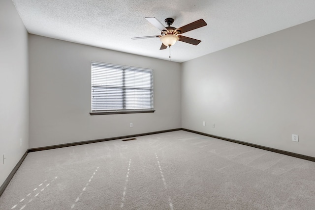 spare room with a textured ceiling, light colored carpet, and ceiling fan