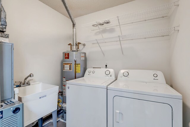 laundry area with water heater, sink, and washer and dryer