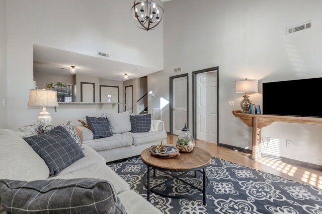 living room with hardwood / wood-style floors, a towering ceiling, and an inviting chandelier