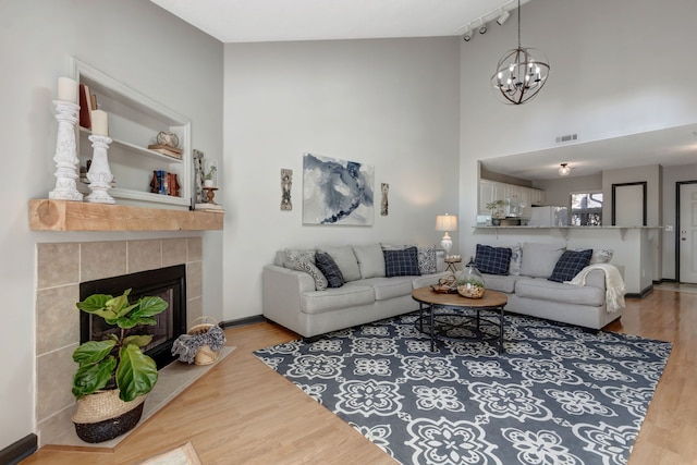 living room featuring hardwood / wood-style flooring, a notable chandelier, a high ceiling, and a tile fireplace