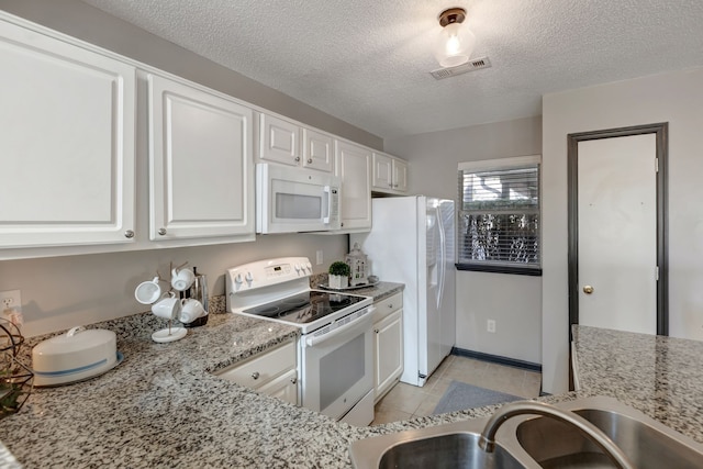 kitchen with light stone countertops, a textured ceiling, white appliances, sink, and white cabinetry