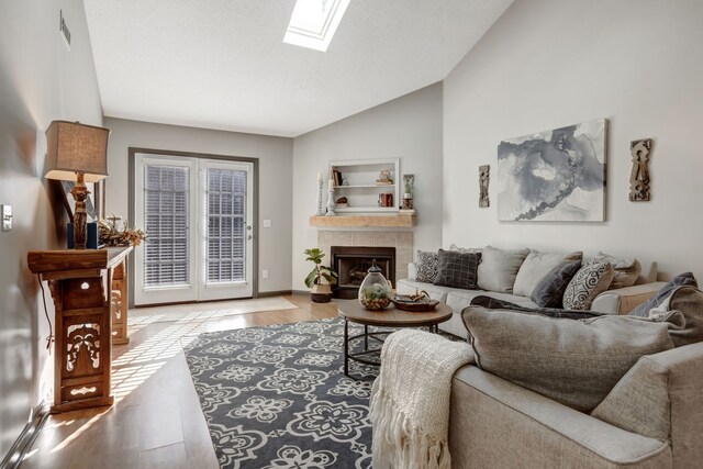 living room featuring a fireplace, lofted ceiling with skylight, and light hardwood / wood-style flooring