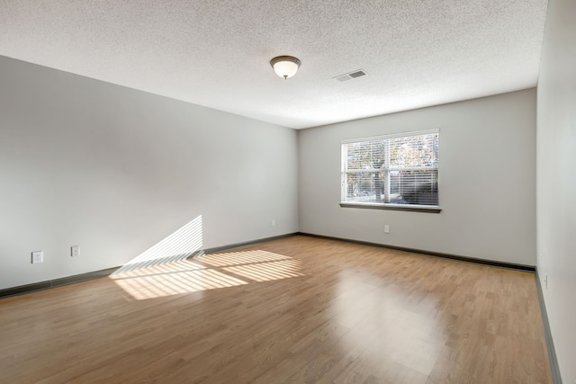 empty room featuring a textured ceiling and light hardwood / wood-style floors