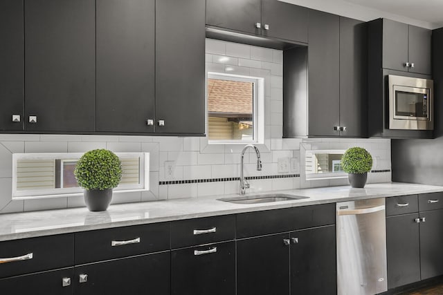 kitchen featuring light stone counters, appliances with stainless steel finishes, sink, and decorative backsplash