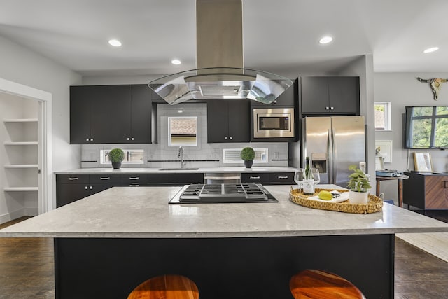 kitchen featuring sink, island range hood, a kitchen island, a kitchen breakfast bar, and appliances with stainless steel finishes