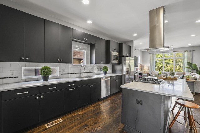 kitchen featuring appliances with stainless steel finishes, island range hood, a kitchen island, dark hardwood / wood-style floors, and sink