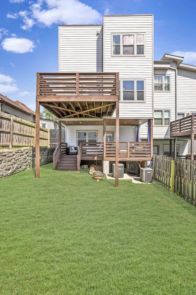 rear view of property with cooling unit, a deck, and a yard