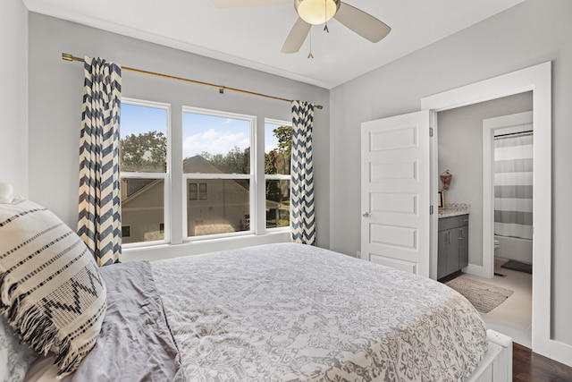 bedroom featuring ceiling fan, ensuite bath, and dark hardwood / wood-style flooring