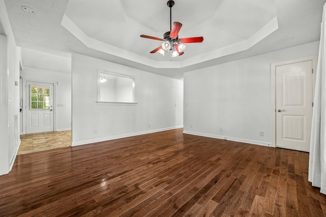 empty room featuring ceiling fan, wood-type flooring, and a raised ceiling