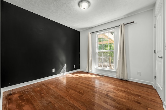 empty room featuring a textured ceiling and wood-type flooring