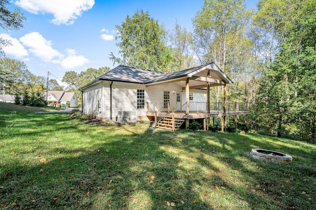 rear view of house featuring an outdoor fire pit, cooling unit, a wooden deck, and a lawn