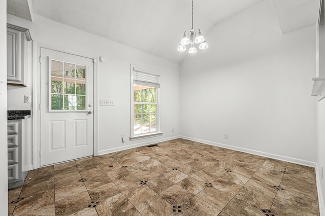 unfurnished dining area with a notable chandelier, a healthy amount of sunlight, and vaulted ceiling