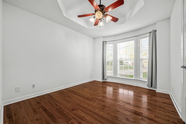 spare room featuring ceiling fan, a tray ceiling, and dark hardwood / wood-style floors