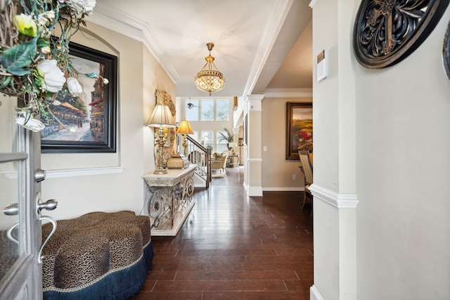 entryway featuring crown molding, a chandelier, dark wood-type flooring, and ornate columns