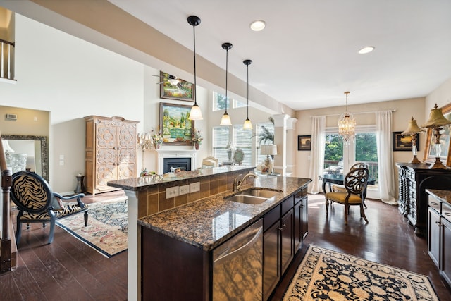 kitchen with a kitchen island with sink, dark wood-type flooring, sink, decorative light fixtures, and stainless steel dishwasher