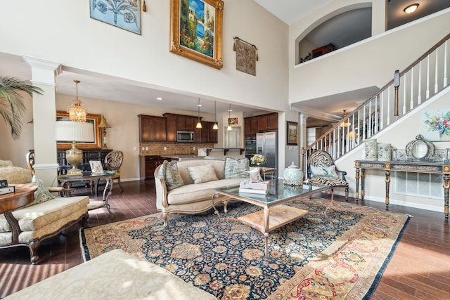 living room featuring a high ceiling, decorative columns, and dark hardwood / wood-style floors