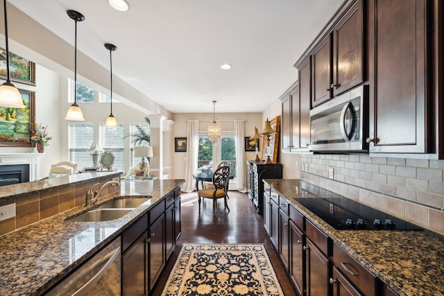 kitchen featuring dark stone counters, dark wood-type flooring, sink, appliances with stainless steel finishes, and decorative light fixtures