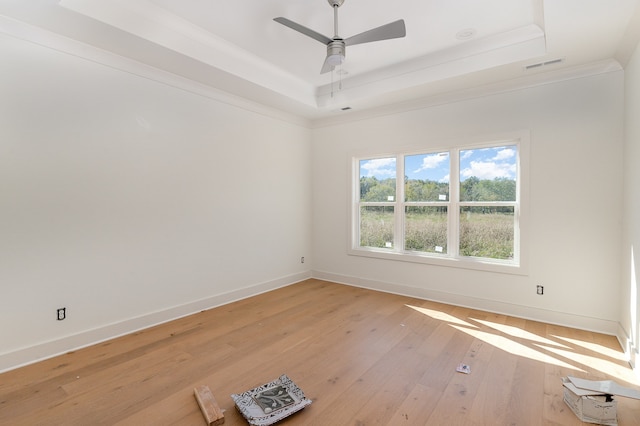 spare room with ceiling fan, light hardwood / wood-style floors, a raised ceiling, and ornamental molding