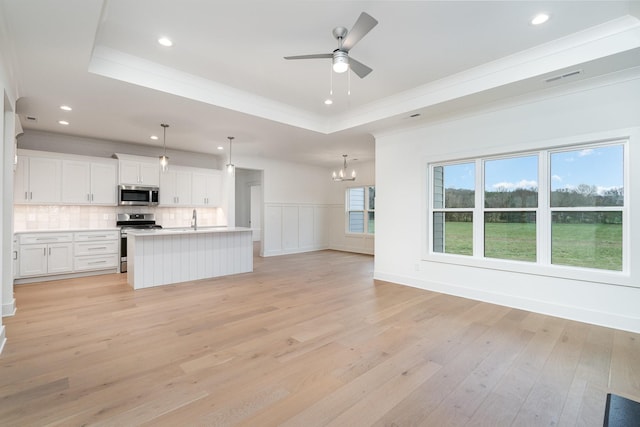 unfurnished living room with a raised ceiling, light hardwood / wood-style flooring, ceiling fan with notable chandelier, and sink