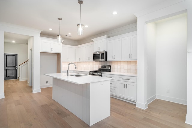 kitchen with white cabinets, appliances with stainless steel finishes, an island with sink, and sink