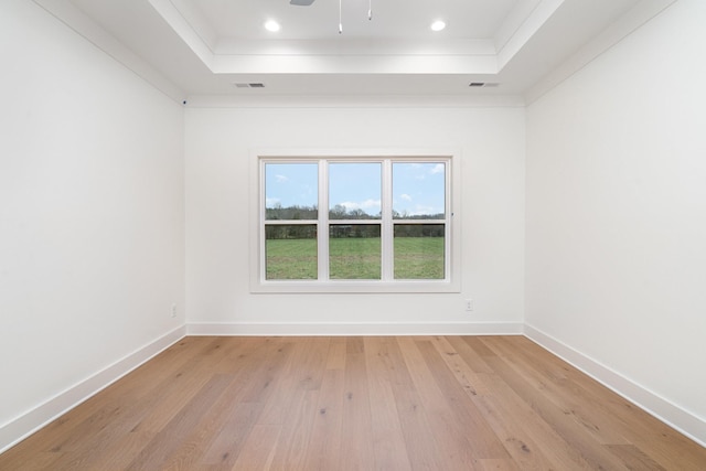 spare room featuring a tray ceiling, ceiling fan, light hardwood / wood-style flooring, and ornamental molding