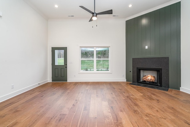 unfurnished living room featuring ceiling fan, a fireplace, light hardwood / wood-style flooring, and ornamental molding