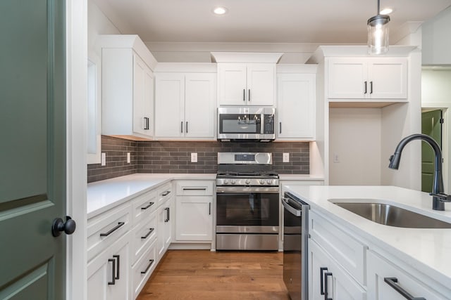 kitchen featuring sink, decorative light fixtures, decorative backsplash, white cabinets, and appliances with stainless steel finishes