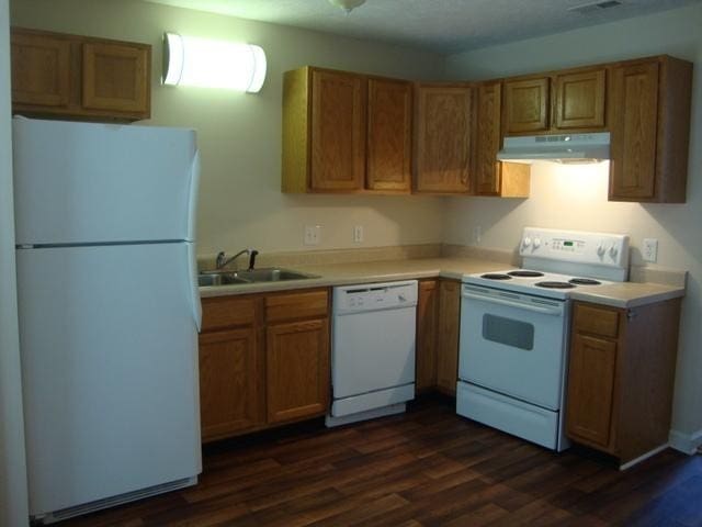 kitchen with white appliances, dark wood-type flooring, and sink