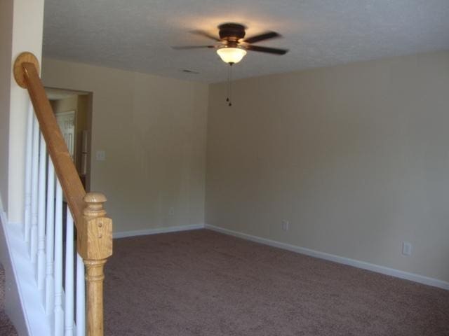 empty room featuring ceiling fan and dark carpet