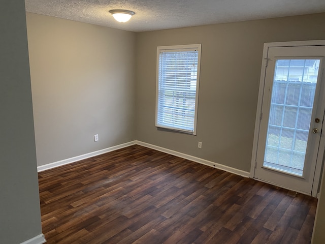 unfurnished room with a textured ceiling and dark wood-type flooring