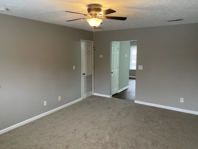 carpeted empty room with ceiling fan and a textured ceiling