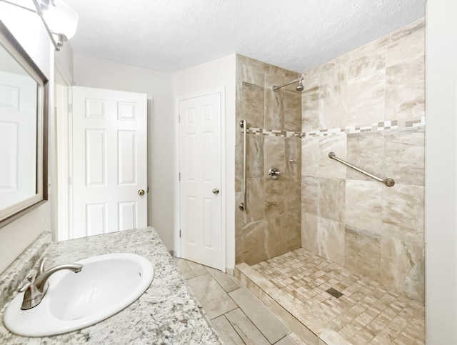 bathroom featuring a tile shower, a textured ceiling, and vanity