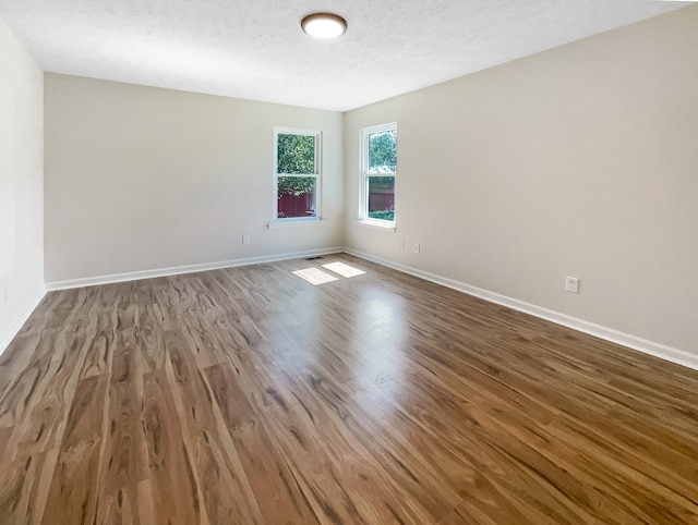 unfurnished room featuring a textured ceiling and hardwood / wood-style floors