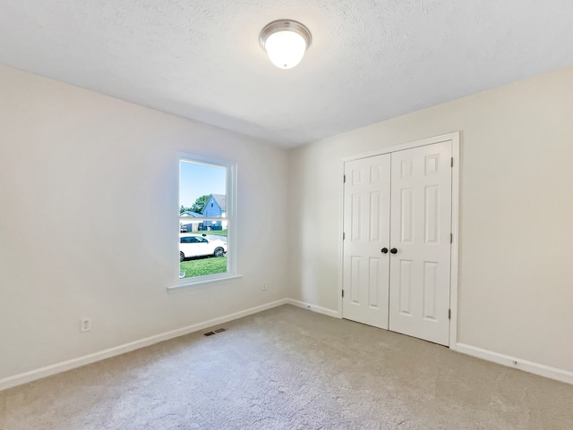 carpeted spare room featuring a textured ceiling