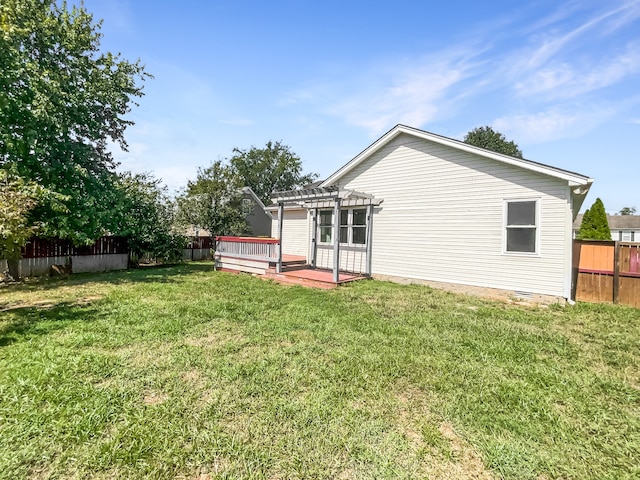 rear view of property featuring a yard, a wooden deck, and a pergola